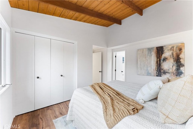 bedroom with beam ceiling, wood ceiling, a closet, and hardwood / wood-style flooring