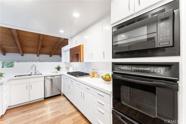 kitchen with beamed ceiling, white cabinets, sink, and black appliances