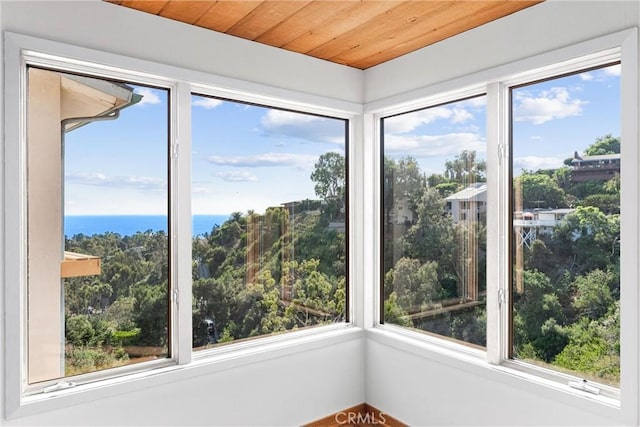 unfurnished sunroom featuring a water view and wooden ceiling