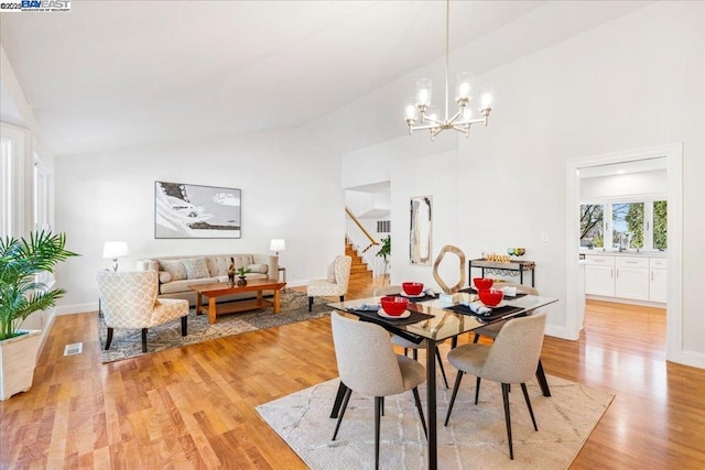 dining space featuring a notable chandelier, light hardwood / wood-style floors, and high vaulted ceiling