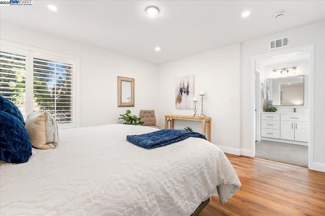 bedroom featuring ensuite bath and light hardwood / wood-style flooring