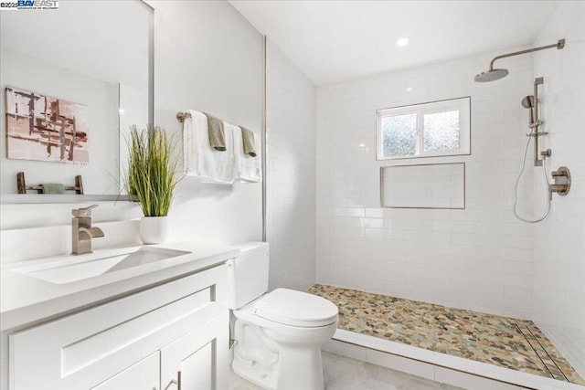 bathroom featuring vanity, toilet, and a tile shower