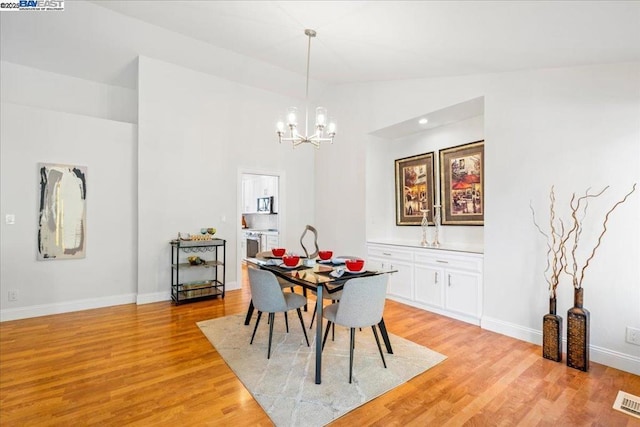 dining area featuring a notable chandelier, light hardwood / wood-style flooring, and vaulted ceiling