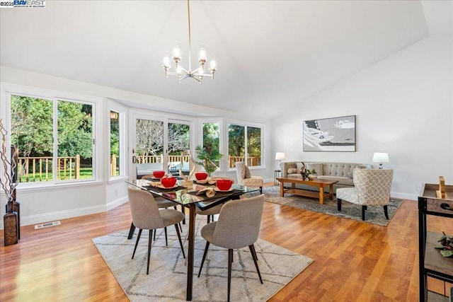 dining room with an inviting chandelier, lofted ceiling, and light hardwood / wood-style floors