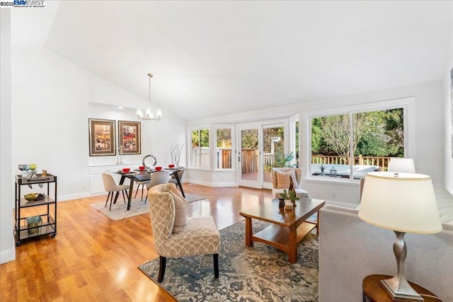 living room with lofted ceiling, an inviting chandelier, and light wood-type flooring