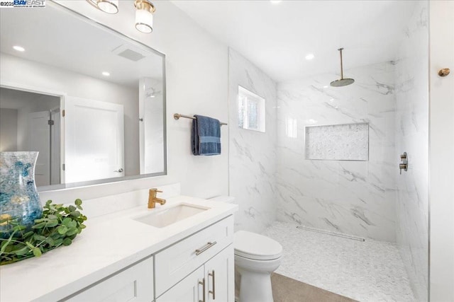 bathroom with vanity, toilet, and a tile shower