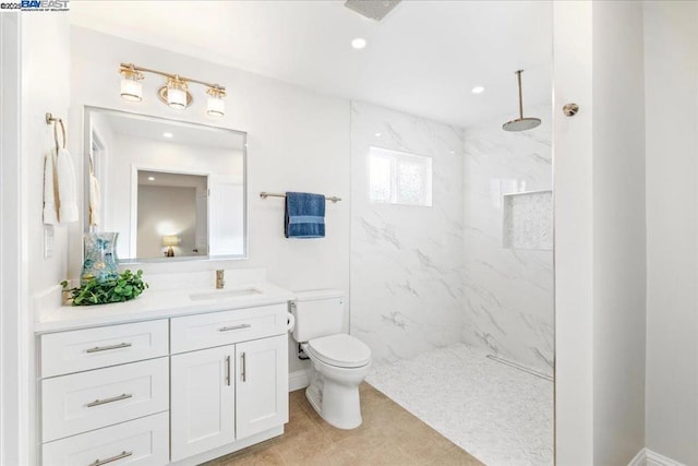 bathroom featuring vanity, tiled shower, tile patterned floors, and toilet