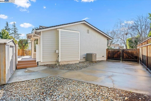 rear view of house with a shed, central AC unit, and a deck