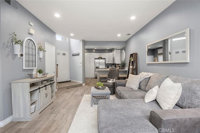 living area with visible vents, recessed lighting, light wood-style floors, and baseboards