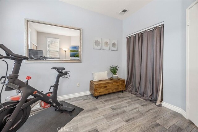 workout room with light wood-style floors, visible vents, and baseboards