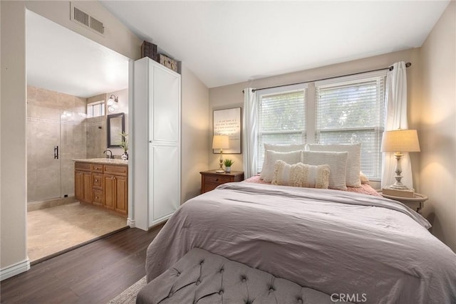 bedroom with dark wood-style floors, baseboards, visible vents, a sink, and connected bathroom