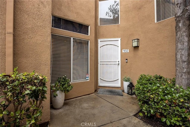 doorway to property featuring a patio area and stucco siding