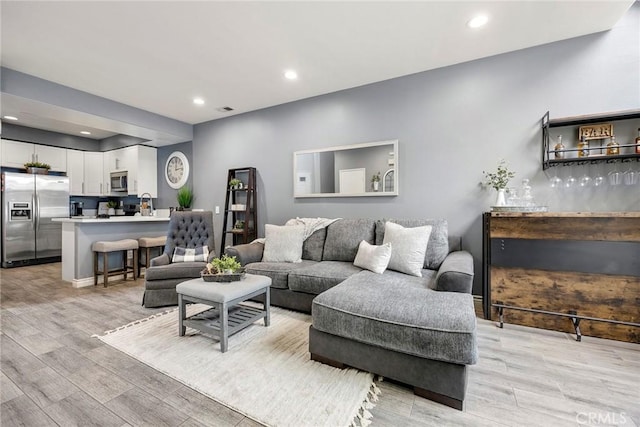 living room featuring light wood-style flooring, recessed lighting, and visible vents