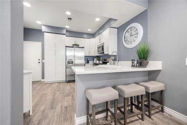 kitchen featuring stainless steel appliances, a peninsula, a breakfast bar, and wood tiled floor