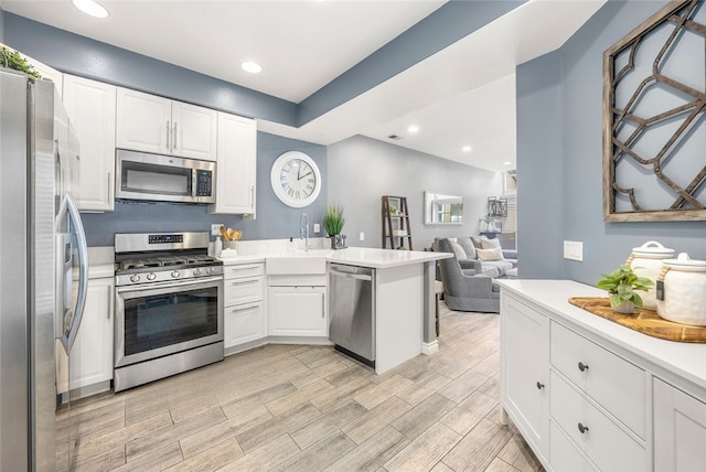 kitchen featuring white cabinetry, stainless steel appliances, kitchen peninsula, and sink