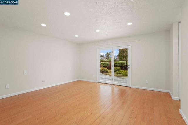 empty room with a textured ceiling and light wood-type flooring