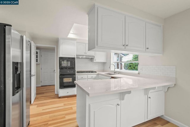 kitchen with sink, white cabinetry, backsplash, black appliances, and kitchen peninsula