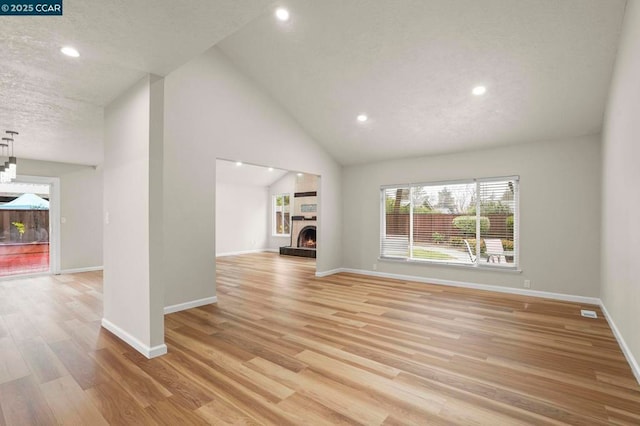 unfurnished living room featuring a textured ceiling, high vaulted ceiling, and light hardwood / wood-style flooring