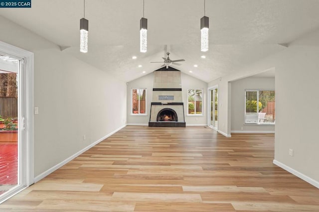 unfurnished living room with ceiling fan, lofted ceiling, a fireplace, and light hardwood / wood-style flooring