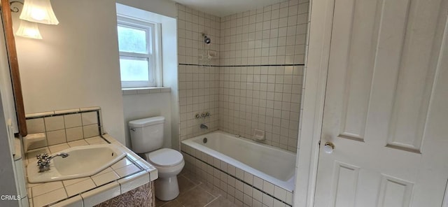 full bathroom with tile patterned flooring, toilet, tiled shower / bath combo, and sink