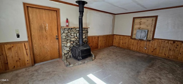 unfurnished living room with carpet floors, a wood stove, and wooden walls