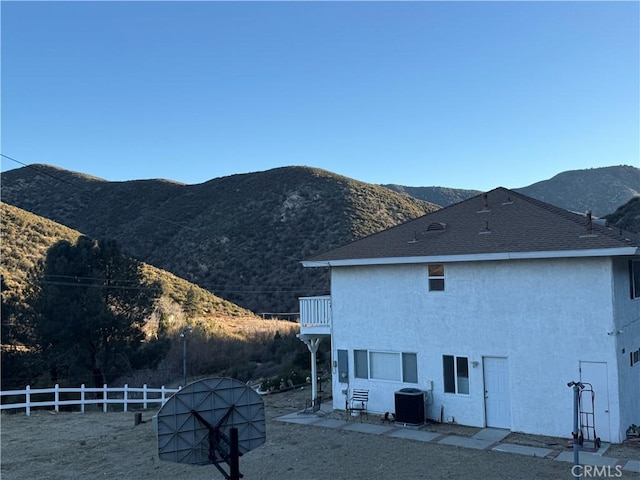 rear view of property with cooling unit, a balcony, and a mountain view