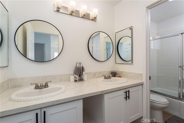 full bathroom featuring vanity, bath / shower combo with glass door, and toilet