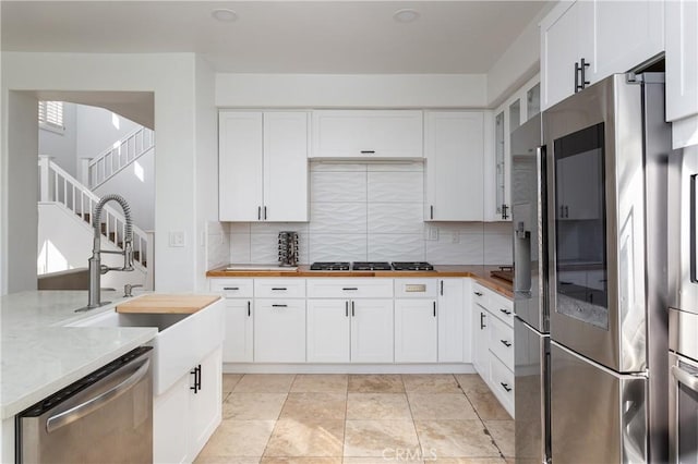 kitchen with backsplash, stainless steel appliances, sink, and white cabinets