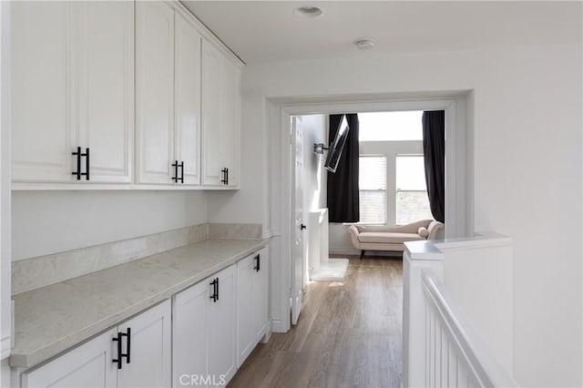 bar with light stone countertops, white cabinets, and light hardwood / wood-style floors