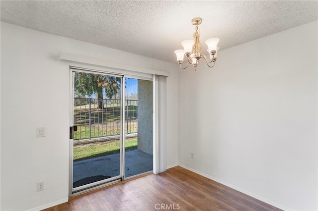 unfurnished room featuring hardwood / wood-style flooring, a textured ceiling, and a chandelier