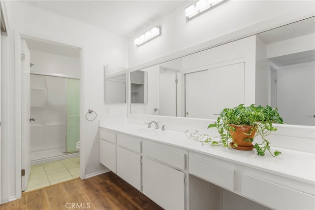 bathroom featuring hardwood / wood-style flooring, vanity, an enclosed shower, a textured ceiling, and toilet