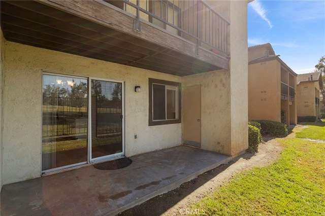 exterior space featuring a balcony, a patio, and a lawn