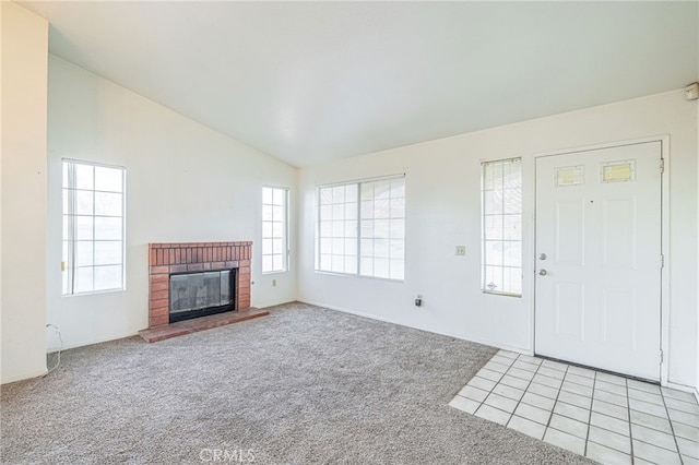 unfurnished living room with light carpet, a brick fireplace, and lofted ceiling