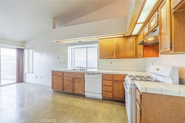 kitchen featuring white appliances, tile counters, a healthy amount of sunlight, and vaulted ceiling