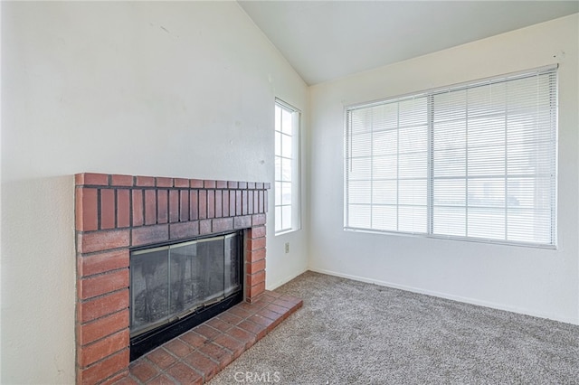 carpeted living room with lofted ceiling, a brick fireplace, and a healthy amount of sunlight