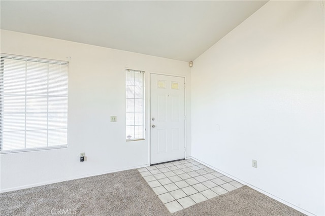 foyer with lofted ceiling and light carpet