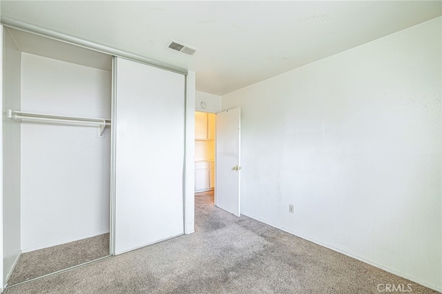 unfurnished bedroom with light carpet and a closet