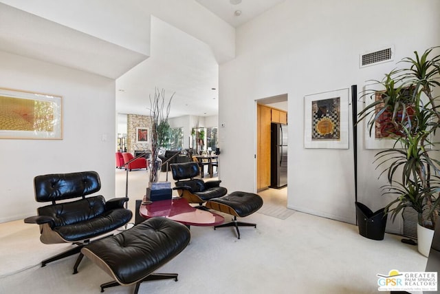 living area with a towering ceiling and light colored carpet