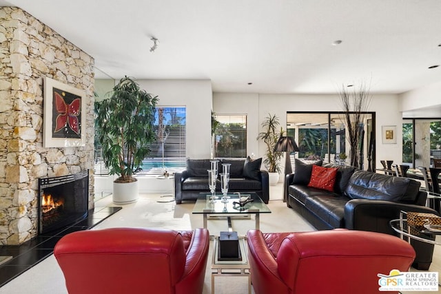 living room with a stone fireplace and plenty of natural light