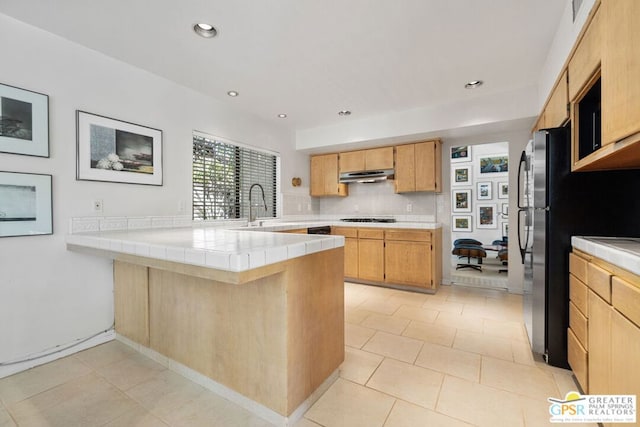 kitchen with sink, gas cooktop, backsplash, tile countertops, and kitchen peninsula