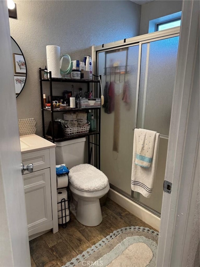 3319 Kellie Ave, Rosamond, CA 93560 - bathroom featuring wood finished floors, a stall shower, toilet, a textured wall, and vanity