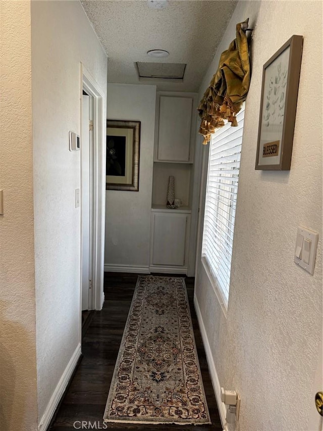 hallway with dark wood-type flooring and a textured ceiling