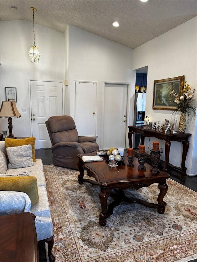 living room featuring hardwood / wood-style flooring, lofted ceiling, and a textured ceiling