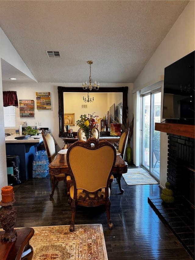 dining area featuring dark hardwood / wood-style flooring, a fireplace, vaulted ceiling, and a chandelier