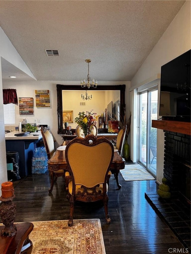 3319 Kellie Ave, Rosamond, CA 93560 - dining area featuring a textured ceiling, lofted ceiling, hardwood / wood-style flooring, a fireplace, and a chandelier