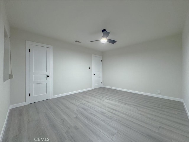 empty room with ceiling fan and light hardwood / wood-style flooring