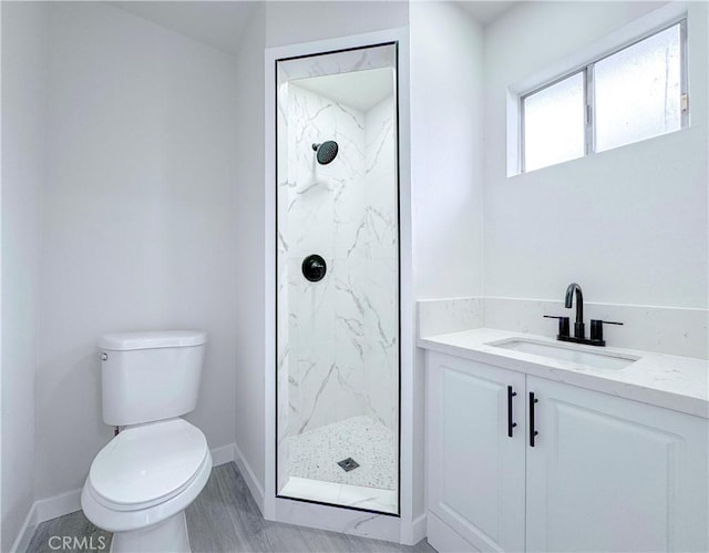 bathroom with vanity, tiled shower, and toilet