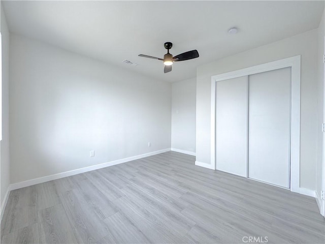 unfurnished bedroom with ceiling fan, a closet, and light wood-type flooring