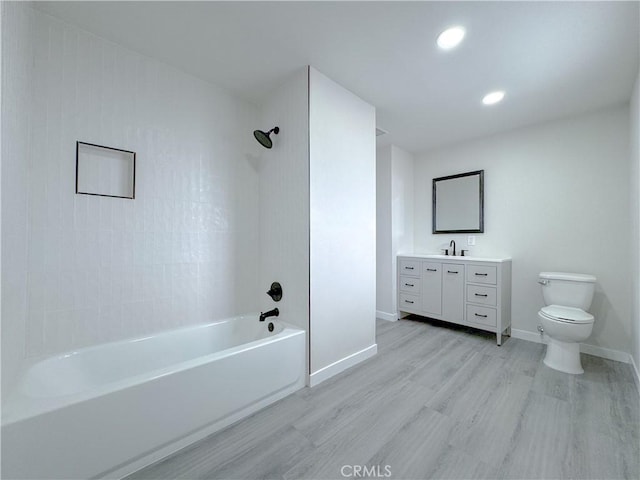 full bathroom featuring vanity, hardwood / wood-style floors, tiled shower / bath combo, and toilet