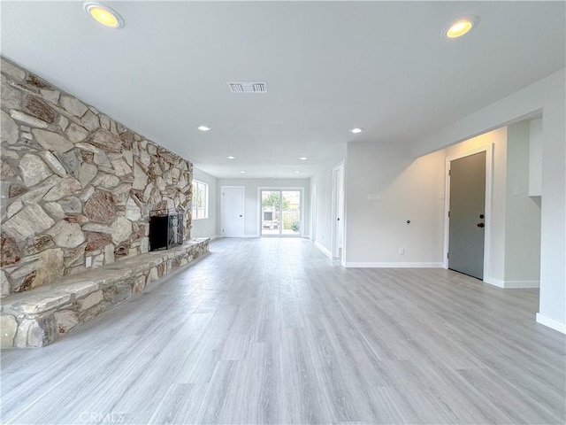 unfurnished living room featuring a stone fireplace and light hardwood / wood-style floors